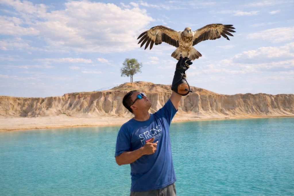 Tourist photo session at Blue Lake Bintan with eagle prop and scenic background